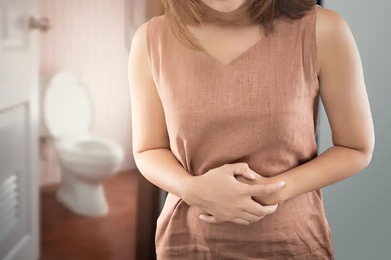 Woman with upset stomach near bathroom